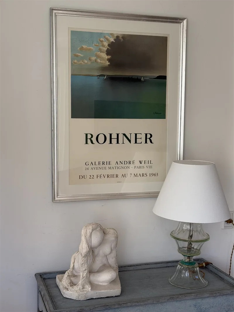 Vintageplakat over konsolbord med gipsskulptur og glaslampe